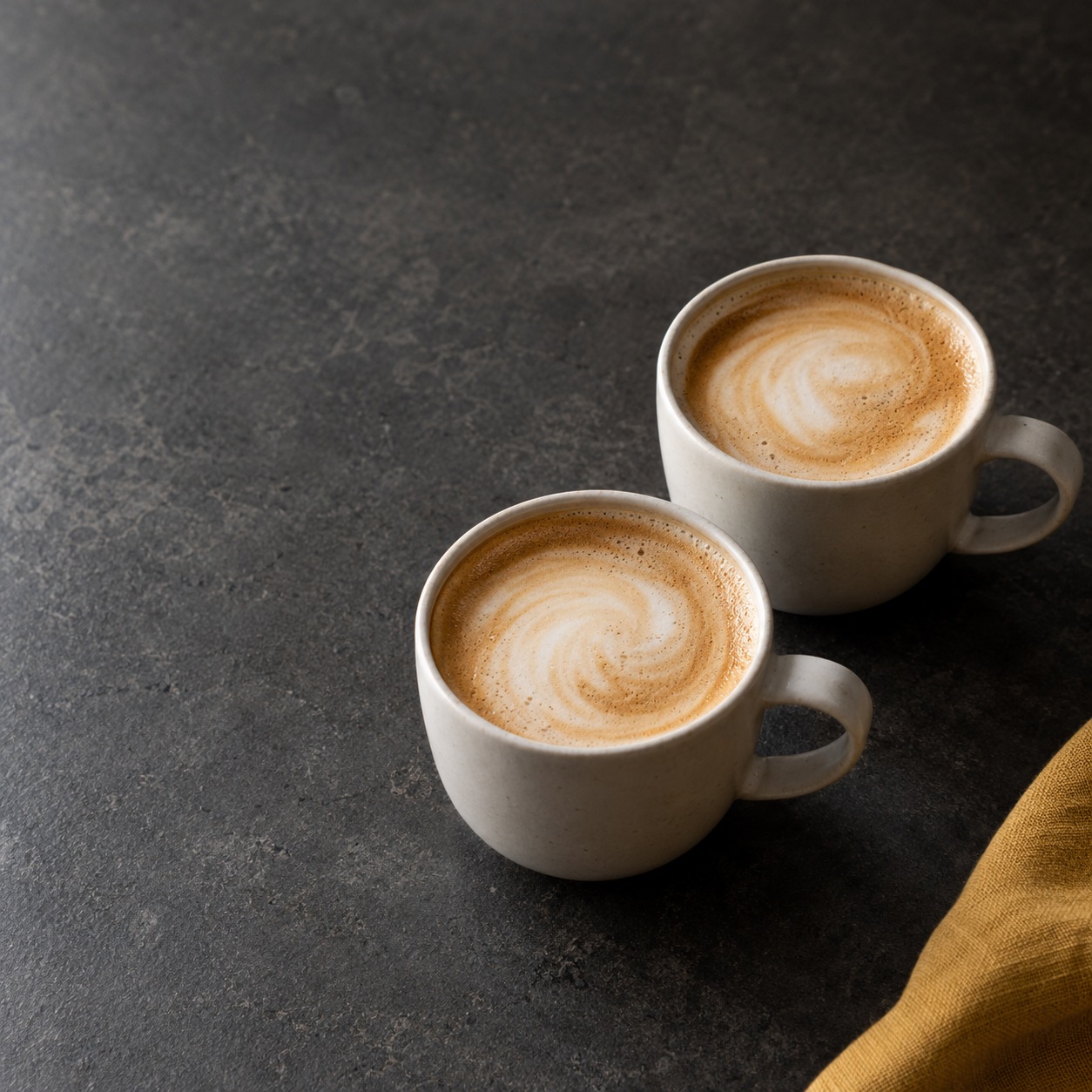 Two cups of latte on a charcoal counter, an editorial illustration