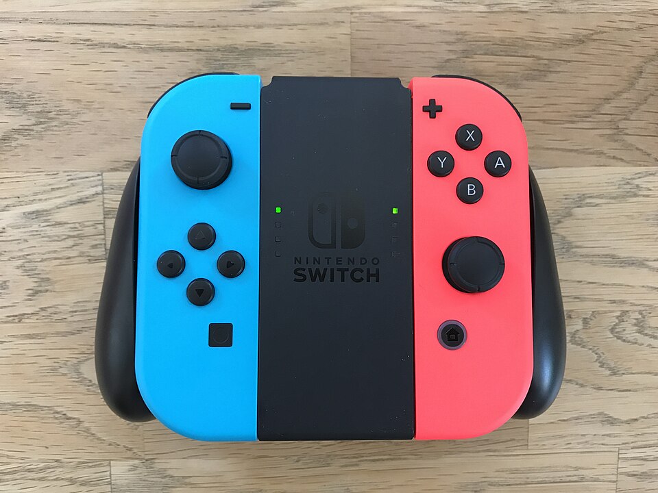 Original blue left and red right Joy-Con attached to a separate black grip on a wooden surface