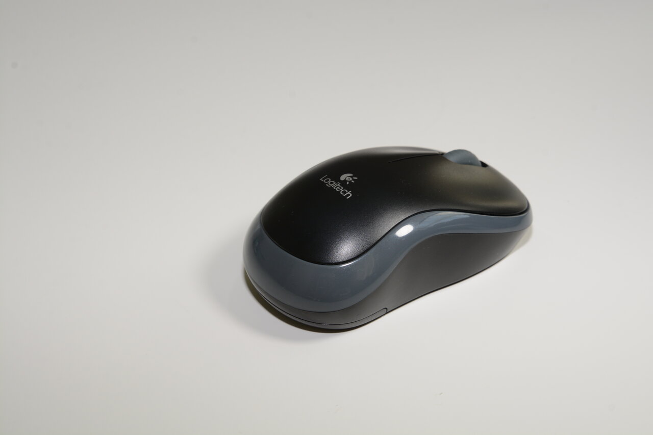 Real black Logitech M185 mouse with gray trim photographed on a light background